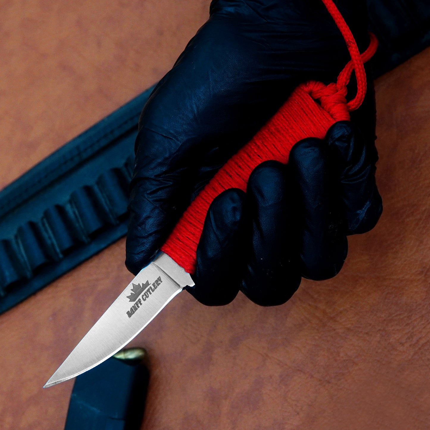 Compact EDC knife with D2 steel blade, ergonomic red paracord grip, and premium leather sheath for everyday carry.