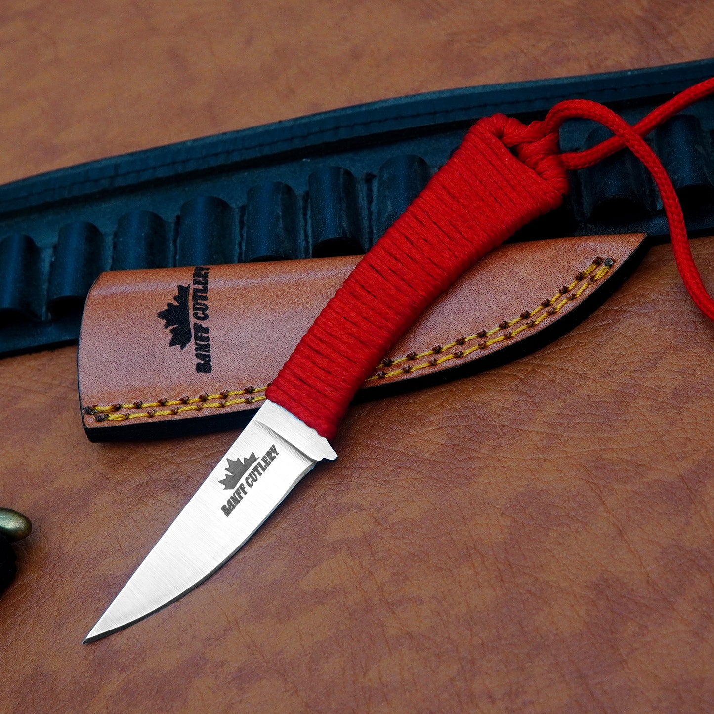 Premium hunting knife with razor-sharp D2 steel blade, red paracord-wrapped handle, and durable leather sheath for precision tasks.