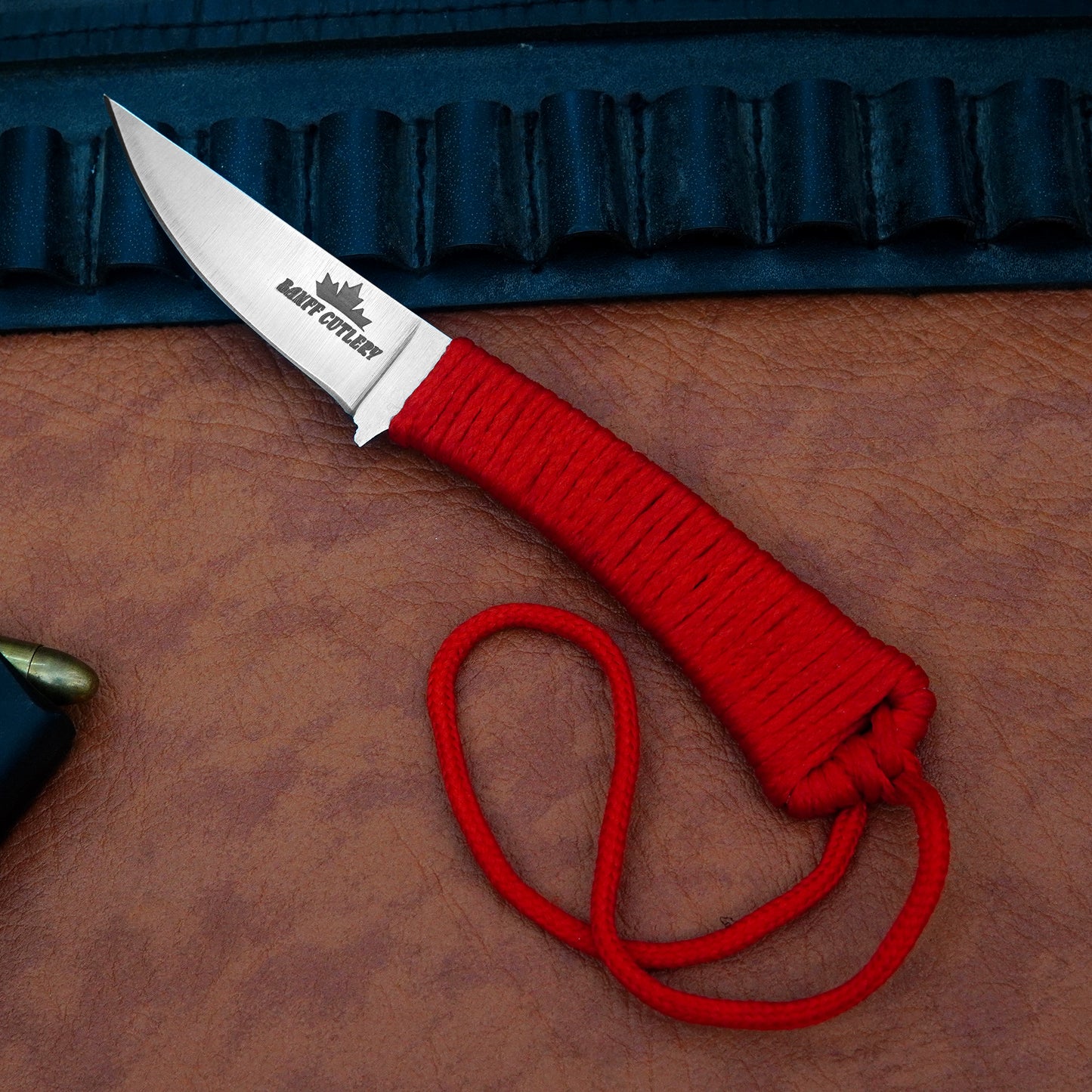 High-performance survival knife featuring D2 steel blade, ergonomic red paracord handle, and leather sheath with steel clip.