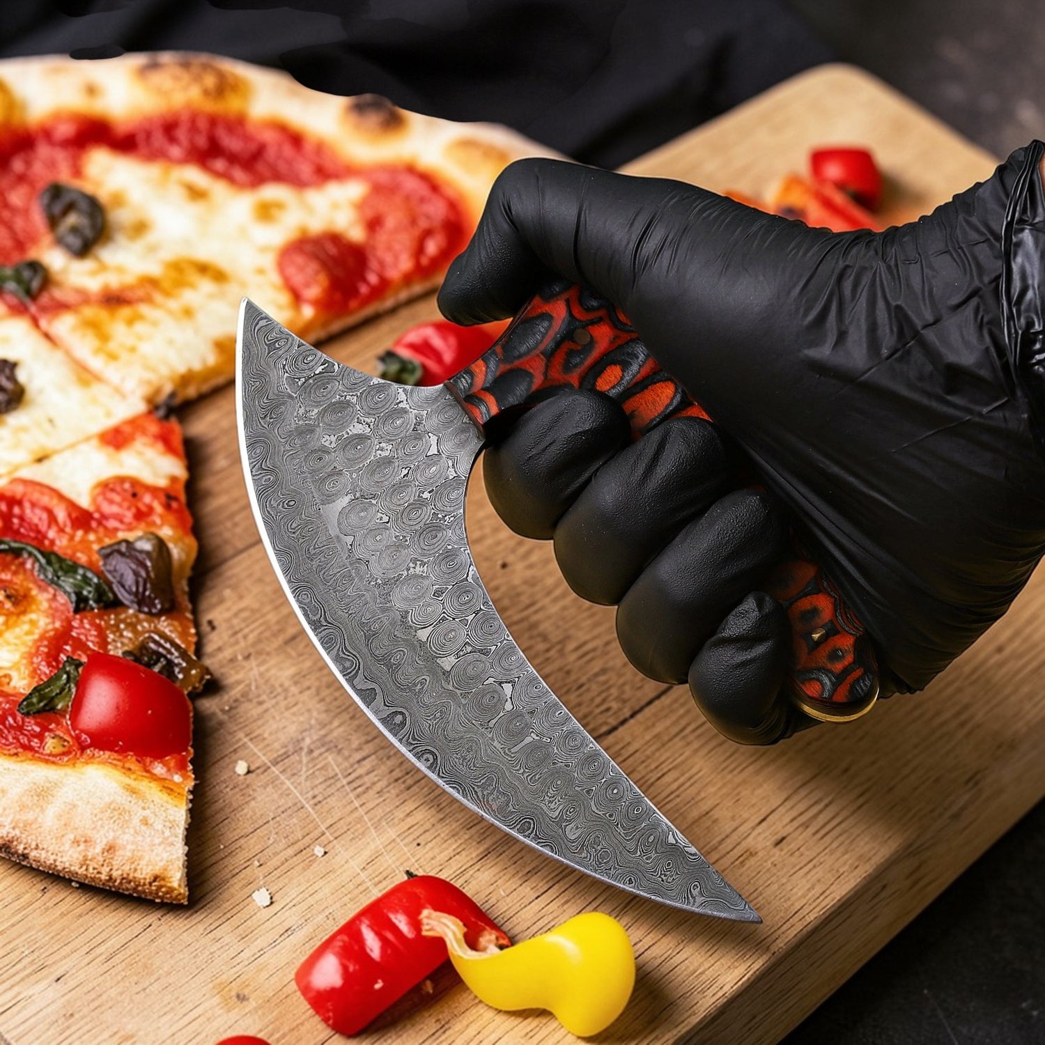 Hand holding a Damascus steel Ulu kitchen knife with patterned blade and ergonomic handle, cutting pizza and vegetables on a wooden cutting board.